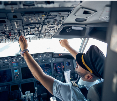 Male pilot in uniform pushing buttons in a cockpit